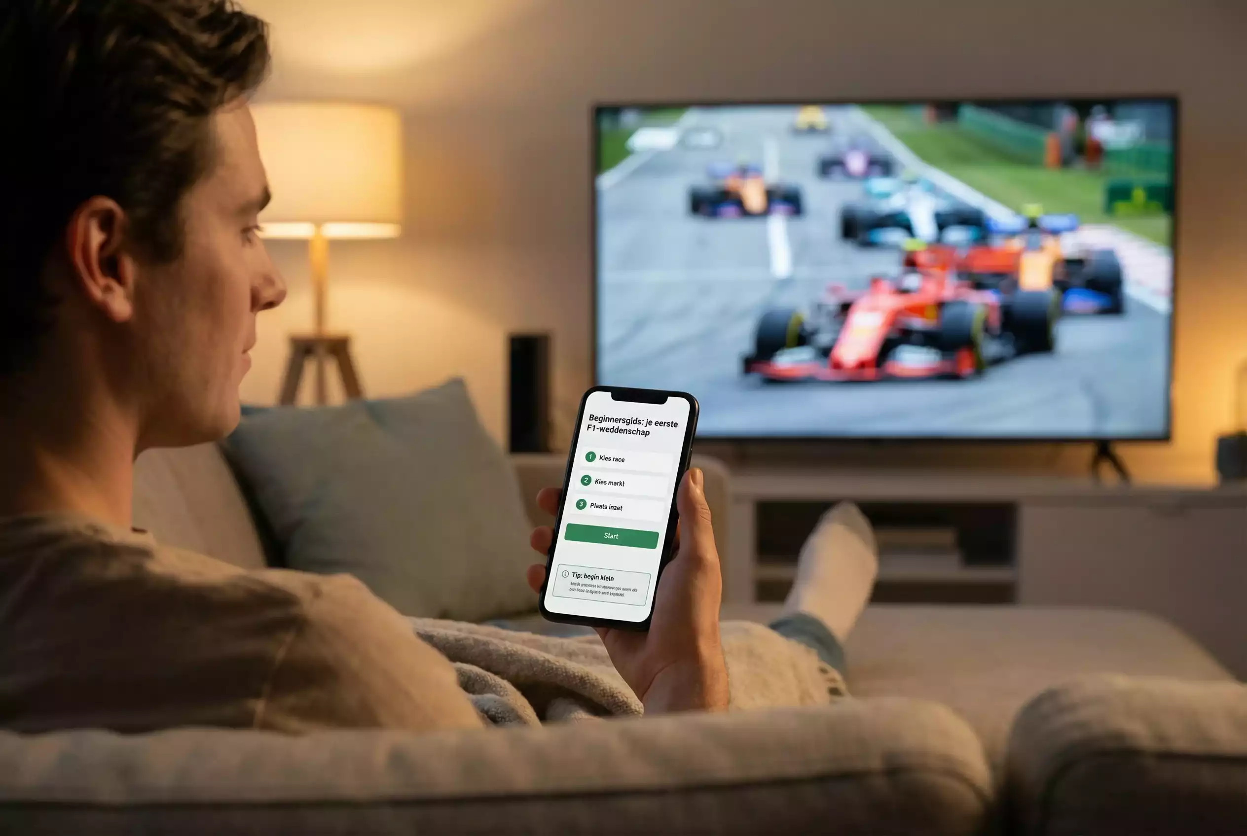 Persoon op de bank met een smartphone en een Formule 1-race op televisie
